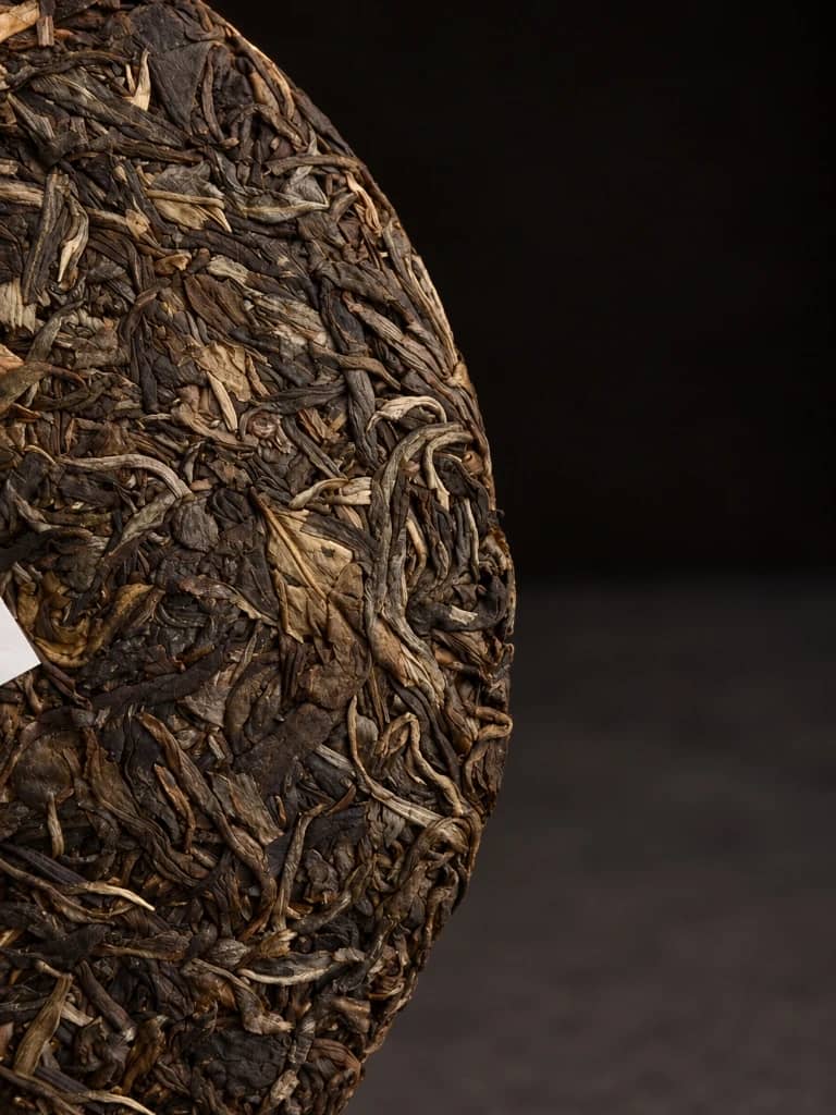 Compressed vintage Shou Pu-erh tea cake showing golden buds