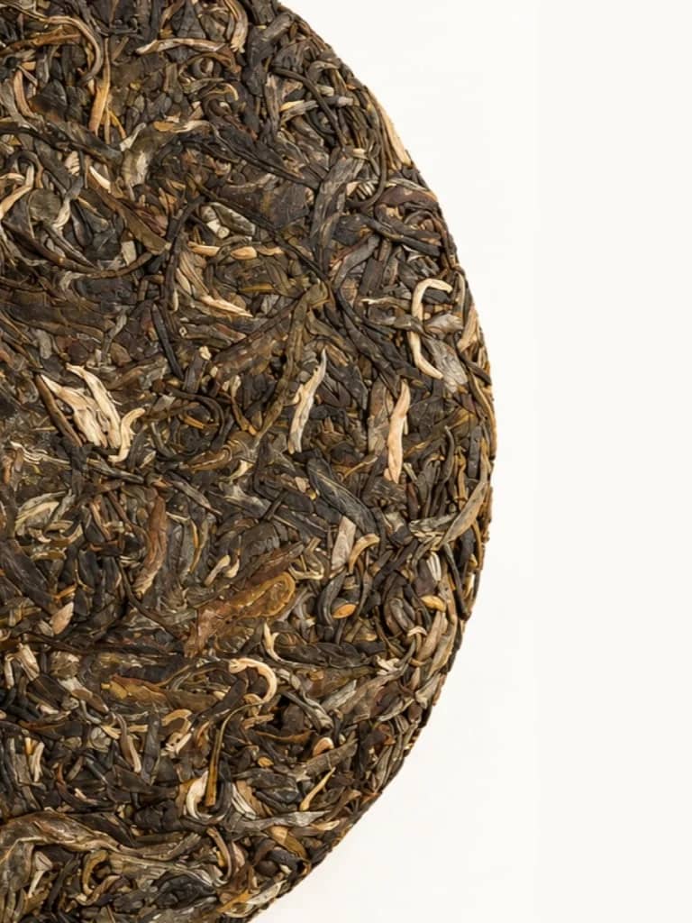Compressed aged 2007 Nanjiao raw pu-erh tea cake showing whole leaves