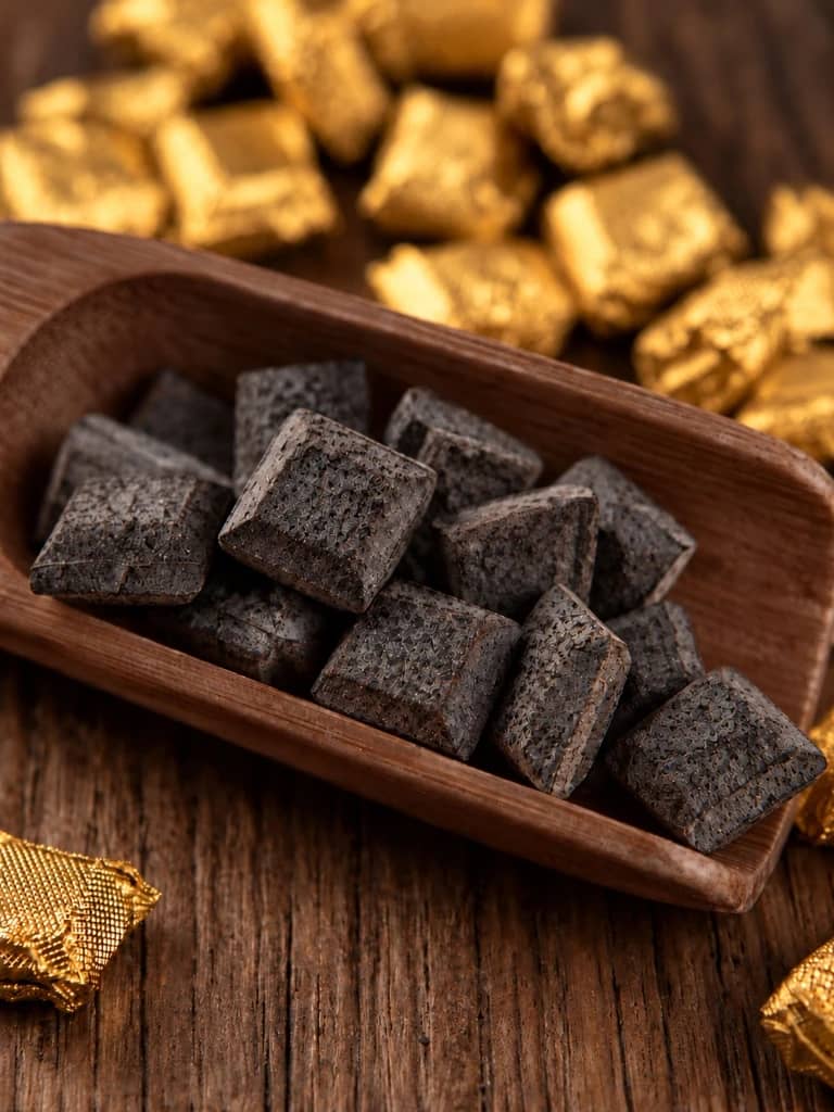 Small glossy crystalline pieces of Pu-erh tea resin (Cha Gao) in a wooden scoop