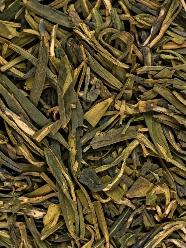 Flat slender green tea leaves close up