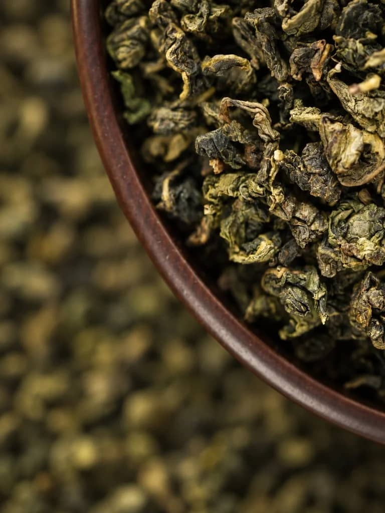 Rolled whole oolong tea leaves in a ceramic bowl